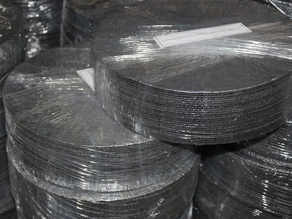 Many round black wire cloth filter discs stacked together
