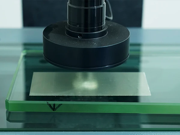 The machine is inspecting the dimensions and uniformity of the woven mesh openings.