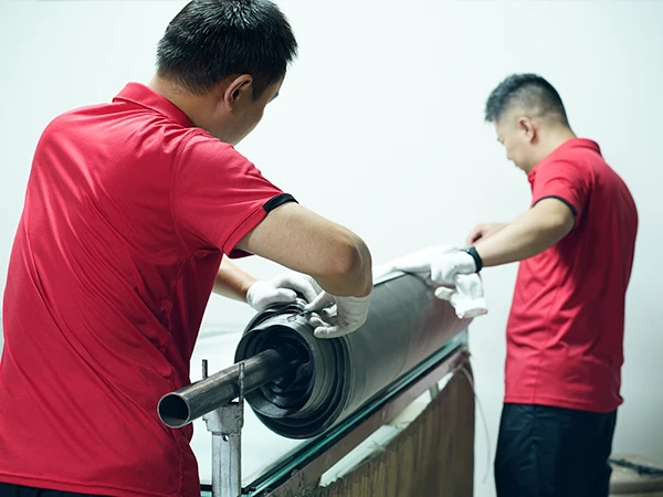 2 workers are measuring the width of a woven wire mesh roll.