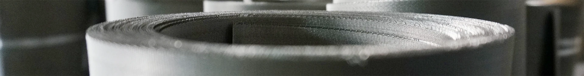 Many rolls of stainless steel dutch weave mesh placed on the ground
