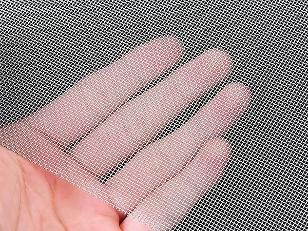 A hand holding a piece of stainless steel plain weave mesh
