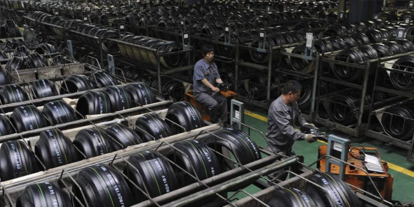 Many tires are placed on the ground, and two people are working.