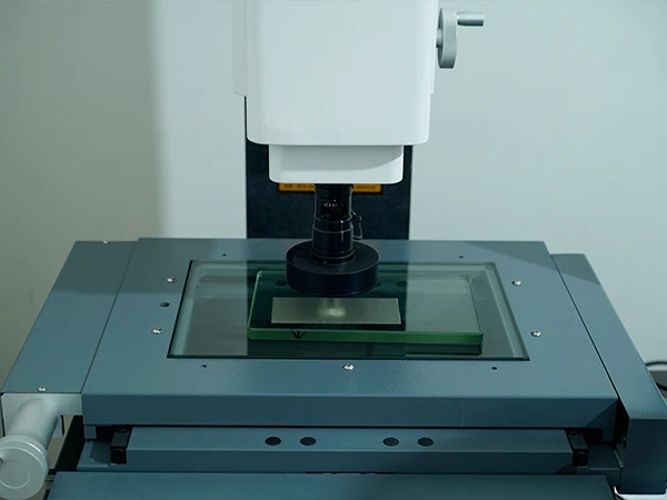 A machine is testing the wire diameter of the woven mesh.