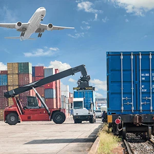 A crane is placing a container onto a truck, and an airplane is flying.
