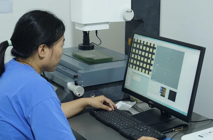 A worker is inspecting the mesh opening of woven mesh on the computer.