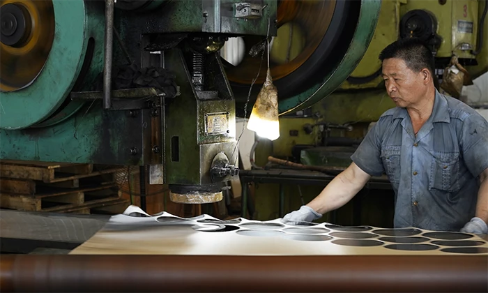A worker is working in front of a woven mesh processing machine.